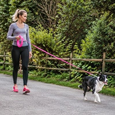 Longe pour Chien femme en promenade avec son chien dans un parc avec la longe rose